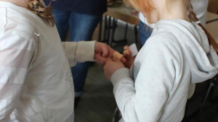 Lina klebt bei ihrer Freundin Astrid ein Pflaster auf.