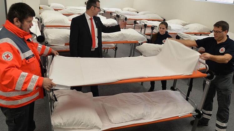 Sven Götz (links), Luisa Popp und Stefan Bergmann bauen ein Doppelstock-Bett in der Flüchtlingsunterkunft auf. Mitte: BRK-Kreisgeschäftsführer Jürgen Dippold. Foto: Ronald Rinklef