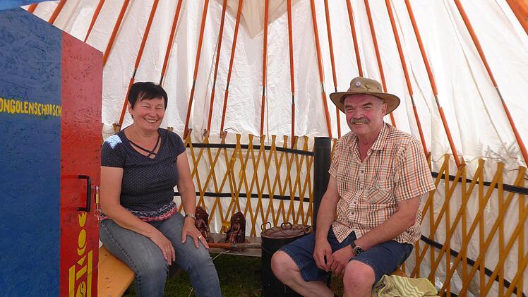 Marianne und Georg Birkel im Innenraum der fertigen Jurte, mit dem kleinen Gusseisenofen, den mongolischen Figuren und der Aufschrift "Mongolenschorsch" auf der Tür Foto: Heidi Amon         