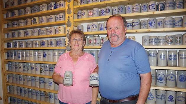 Maria und Hans Fehn vor einer großen Wand mit Bierkrügen im  Keller ihres HausesHeike Schülein