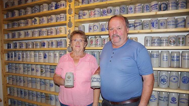 Maria und Hans Fehn vor einer großen Wand mit Bierkrügen im  Keller ihres HausesHeike Schülein