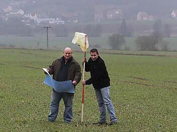 Klaus Schebler (links) und  Fabian Nöth markieren den Standort eines Windrades. Im Hintergrund ist Burghausen zu sehen. Fotos: Björn Hein