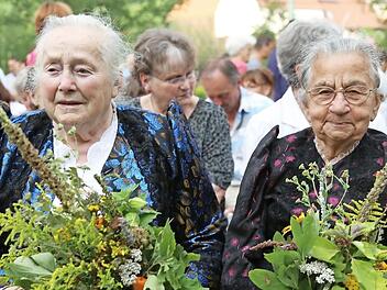 In Tracht und mit Würzbüscheln in der Hand nehmen diese zwei Frauen am Gottesdienst teil.