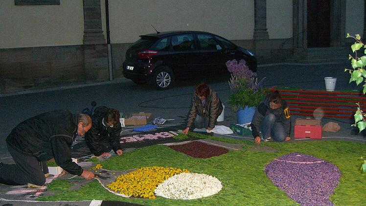 Ganz leise im Dunkeln legten die Stadtsteinacher den Teppich - der Kirchplatz wurde von Autoscheinwerfern erleuchtet. Foto: Sonny Adam