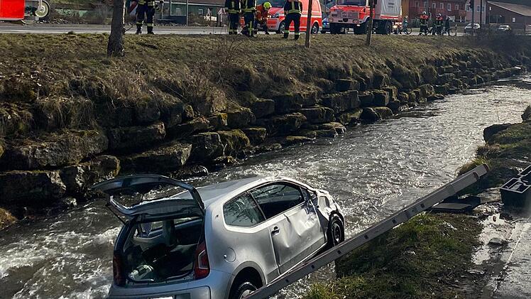 Der verunglückte Wagen in der Sinn.  Der Fahrer konnte sich nicht selbstständig aus dem Auto befreien.