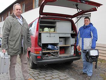 Die Brandfahnder Bernhard Köder (links) und Mirco Böhm mit ihrem Einsatzfahrzeug: Seit 17 Jahren tut das Auto bereits seinen Dienst. Es enthält Werkzeug, Messgeräte und weitere Utensilien, die für die aufwendige und umfangreiche Arbeit der Ermittler erforderlich sind.  Foto: Helmut Will