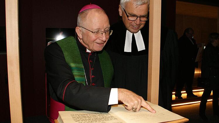 Eine besondere Bibel steuerte Weihbischof Ulrich Boom (links) für die Dauerausstellung "Auf der Spur von Jesus" bei. Sie ist von ihm handgeschrieben. Seinem "Amtsbruder" Landesbischof i.R. Johannes Friedrich erläuterte er, welche Bibelabschnitte ihm dabei besonders wichtig waren.  Foto: Sabine Weinbeer