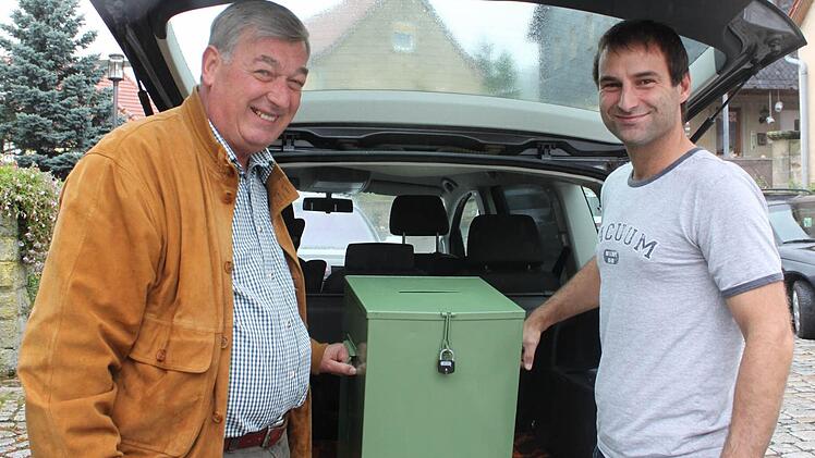 Werner Schneider und Markus Frank holen die wertvolle Fracht aus dem Kofferraum. Am Sonntagmittag fuhr Markus Frank die Wahlurne von Bischofsheim nach Sechsthal. Die beiden Orte teilen sich eine Urne, damit die Stimmzettel gemischt werden und das Wahlgeheimnis gewahrt wird. Fotos: Carmen Schmitt