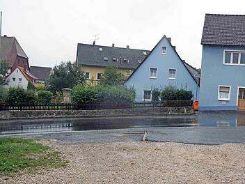 Die Brache im Vordergrund und die gegenüberliegende Fläche mit Kriegerdenkmal und Grabstein auf dem ehemaligen Kloster-Friedhof sollen zur neuen Ortsmitte von Münchaurach umgestaltet werden. Foto: Sänger