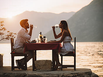 Ein Paar genießt ein privates Dinner-Event an einem tropischen Strand während des Sonnenuntergangs.