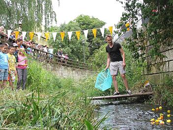 Viele Besucher beim Pfarrfest verfolgten das erste Ebelsbacher "Entenrennen" auf dem gleichnamigen Bach. Florian Mayer (rechts) schickte jeweils 20 Gummi-Tiere auf die 80 Meter lange Reise. Und schon ging die rasante Fahrt auf dem Bach los.  Foto: Ralf Naumann