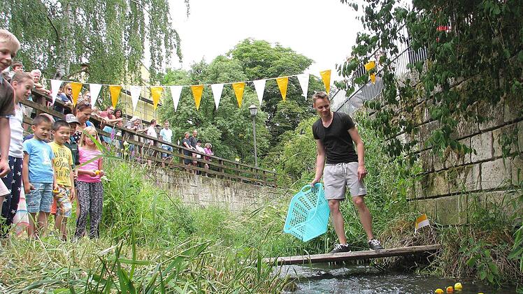 Viele Besucher beim Pfarrfest verfolgten das erste Ebelsbacher "Entenrennen" auf dem gleichnamigen Bach. Florian Mayer (rechts) schickte jeweils 20 Gummi-Tiere auf die 80 Meter lange Reise. Und schon ging die rasante Fahrt auf dem Bach los.  Foto: Ralf Naumann
