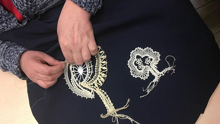 Eine Angestellte des Ladens "Mode macht Mut" veredelt ein Kleidungsstück für die Ausstellung, in dem sie Klöppelspitze aufnäht. Foto: Annabelle Gunzelmann