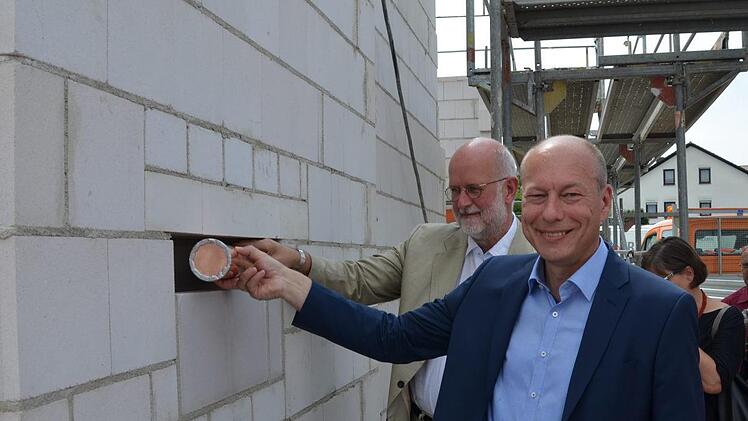 Die Kapsel wurde von Bürgermeister Michael Karmann (im Vordergrund) zusammen mit Christoph Gatz in einer Wand in der Kindertagesstätte versenkt.Andrea Spörlein