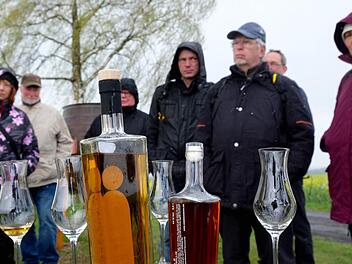 Bei einsetzendem Schneegestöber gab es Franziska Bischofs Informationsvortrag über den Rhöner Whisky am Dreimärker-Kreuz. Die Wanderer ließen sich nicht vom Besuch abhalten und erhielten zur Belohnung einen Schluck aus dem Probierglas. Foto: Gerd Schaar