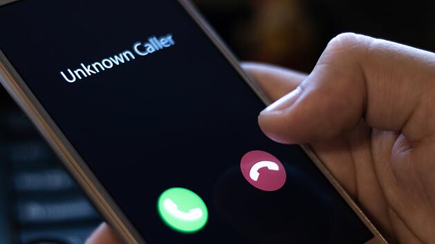 Unknown caller. A man holds a phone in his hand and thinks to end the call. Incoming from an unknown number at night. Incognito or anonymous Unbekannter Anrufer. Ein Mann h&auml;lt ein Telefon in der Hand und &uuml;berlegt, den Anruf zu beenden. Nachts von einer unbekannten Nummer. Inkognito oder anonym.