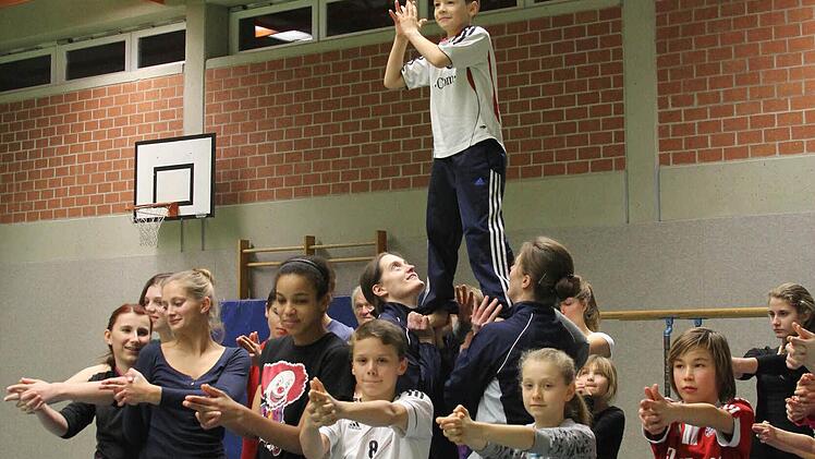 Er hat die beste Aussicht: der neunjährige Gabriel (oben). Vorne Cara, Luna, Richard, Elena und Leon, ebenfalls in James-Bond-Pose, dahinter die Trainerinnen Sabine und Heidi Diener, die Gabriel in lichte Höhen heben. Foto: Gerd Ludwig