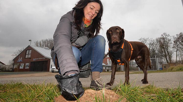 Stefanie Diller packt beherzt mit einem Plastikbeutel zu. Hund "Jasper" schaut Frauchen beim Saubermachen zu. Foto: Ronald Rinklef
