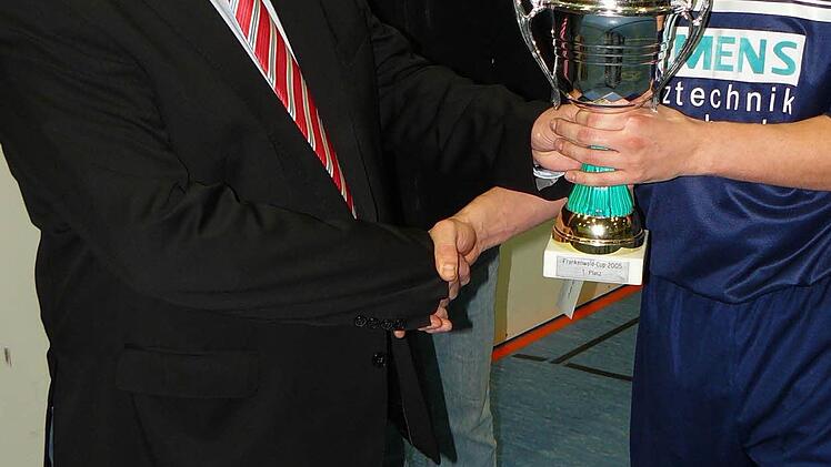 Bürgermeister Norbert Volk (links) überreicht dem Marktleugaster Kapitän Oliver Turbanisch (rechts) den Siegespokal. Dazwischen FC-Vorsitzender Klaus Witzgall.