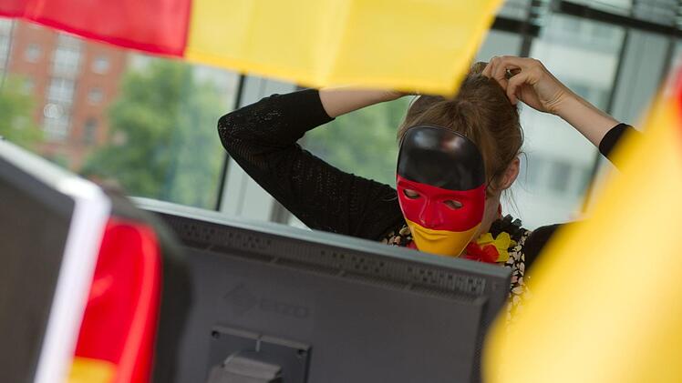 Wenn das ganze Büro in Schwarz-Rot-Gold geschmückt ist, haben die WM-Muffel keine Chance mehr. Wie ihr trotzdem unbeschadet aus der Nummer rauskommt. Foto: Andrea Warnecke/dpa