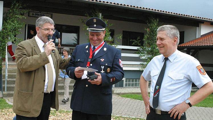 Der "Tag der Helfer und Retter" war von Kreisbrandrat Manfred Lorenz (rechts) als Werbung für den ehrenamtlichen Nachwuchs geplant. Doch während sich der Kommandant der nun 100-jährigen Freiwilligen Feuerwehr Dietersdorf Wolfgang Brasch (Bildmitte) noch über den Scheck von Landrat Michael Busch freute, zogen am Himmel über dem Sportplatz bereits die Gewitterwolken auf, die allen geplanten Aktionen ein Ende setzen sollten.