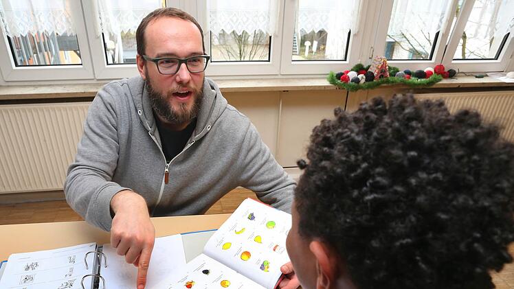 Ein 14-jähriger unbegleiteter Flüchtling aus Eritrea wird bei seinen Deutsch-Hausaufgaben von einem Erzieher betreut.  Foto: Karl-Josef Hildenbrand, dpa