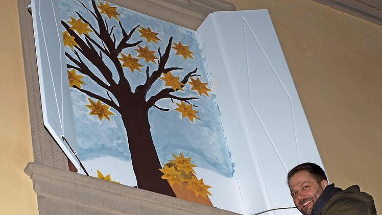Elternbeiratsvorsitzender Christian Schober öffnete das erste Adventsfenster, hinter dem sich ein Baum mit goldenen Sternen zeigte.