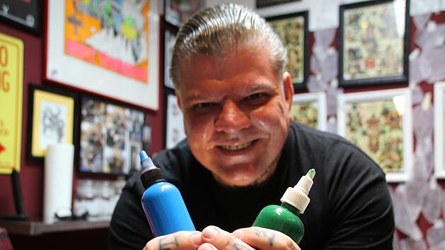 Der Bad Kissinger Tätowierer Jörg Sauer mit grüner und blauer Farbe. Foto: Johannes Schlereth
