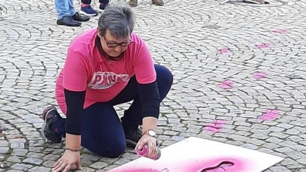 Claudia Weber sprayt pinke Fußabdrücke auf den Bad Brückenauer Marktplatz. Foto: Christine Wolf