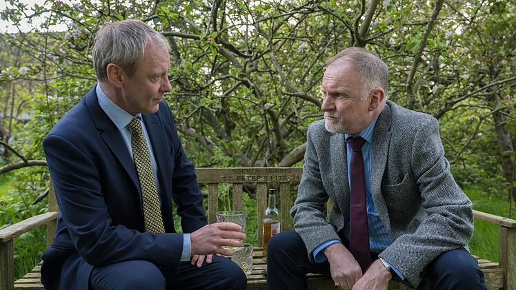 DS Roy Grace (John Simm, links) befragt Gavin Daly (Robert Glenister), den Bruder des Opfers, über eine geheimnisvolle Uhr.
