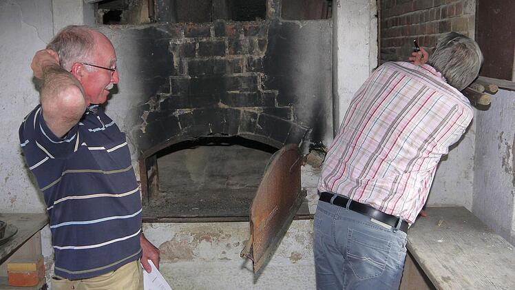 Da zweifelt jemand: Während Herwig Schmidt (links) über die Kosten der Sanierung des Herrether Backhauses grübelt, betrachtet Jürgen Alt den Zustand des Ofens.  Foto: Berthold Köhler