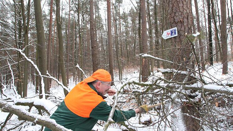 Gerhard Beck hat ein Holzlos in der Waldabteilung "Windsburg". Bevor er mit der Motorsäge kommt, arbeitet er sich mit dem Beil durch das gefällte Holz, damit der Wanderweg schnell wieder frei wird. Fotos: Heike Beudert