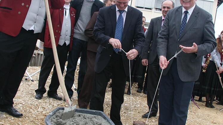 Ein geschichtsträchtiger Moment: Bürgermeister Herbert Schneider (rechts) und Landrat Oswald Marr versenken die Zeitkapsel. Holger Pohl wartet schon darauf, das Loch zuzufüllen. Mit im Bild (von links): Vorsitzender Michael Scheler, Peter Heinz von der Baufirma Mühlherr, Dritte Bürgermeisterin und Ehrenvorsitzende Helga Mück sowie der stellvertretender Bezirksvorsitzender des Nordbayerischen Musikbundes, Thomas Kolb.  Fotos: Sonja Adam