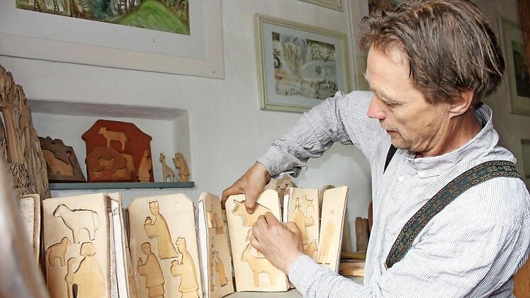 Eckart Henzler und eines seiner Baumstammbücher. Sie sind aus einem Stammstück gefertigt, aufklappbar und enthalten einzelne Figuren.