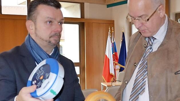 Jochen M&uuml;ller (l.) und B&uuml;rgermeister Klaus Homann inspizieren einen Defibrillator. Foto: A. Sp&ouml;rlein