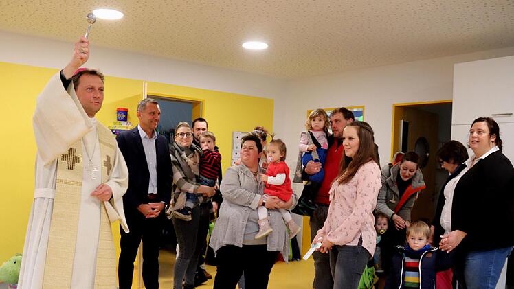 Der Weihbischof besprengt die neuen Räume mit Weihwasser.