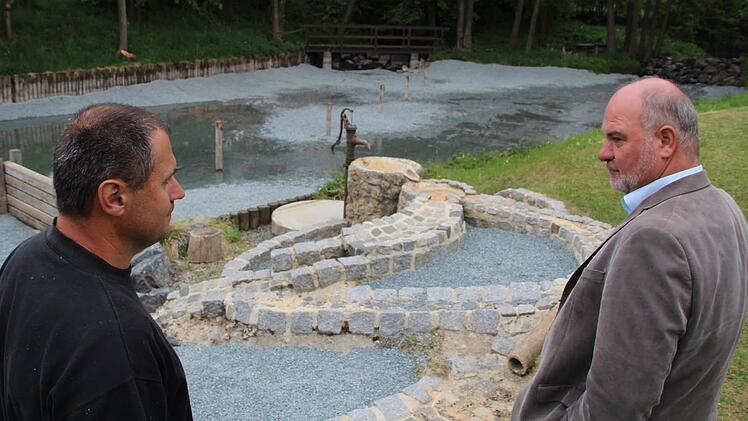 Bürgermeister Ralf Holzmann (rechts) und Bauhofmitarbeiter Christian Burdich besprechen am sanieren Naturbadeweiher die letzten Arbeiten vor Beginn der neuen Saison. Foto: Matthias Beetz