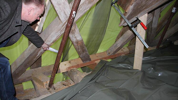 Bürgermeister Helmut Blank zeigt auf Dachbereiche, die notgesichert wurden, damit der Dachstuhl neue Stabilität erhält. Foto: Heike Beudert