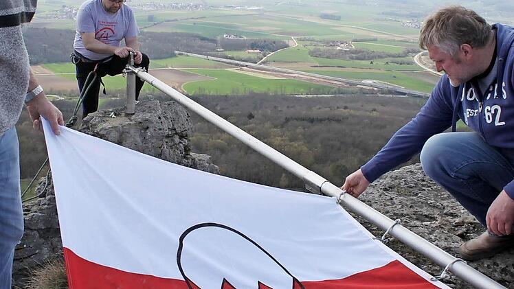 Gemeinsam wird die neue Fahne am Mast befestigt.