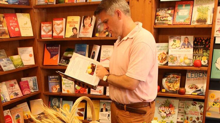 Steffen Vogel blättert im Buch. Auf den Seiten 94 und 95 sind sein Lieblingsgericht und seine Aussagen zum Glauben zu finden.  Foto: Klaus Schmitt