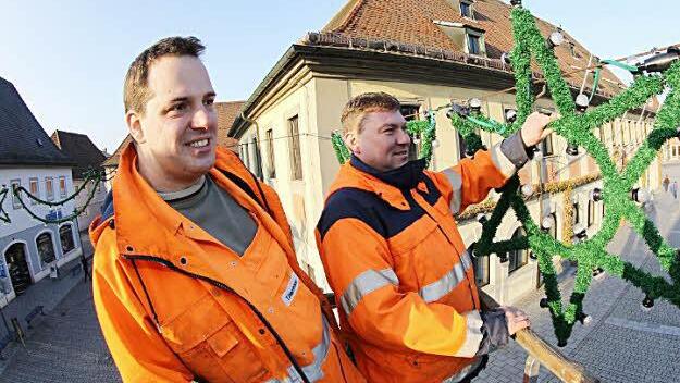 Tobias Herrmann und Rainer Schütz hängen die Weihnachtsbeleuchtung am Rathaus auf.