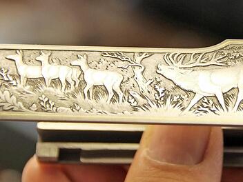 Hirsch und Eichenlaub in einer klassischen Waldszene sind typische Motive, die eine Jagdwaffe des hochpreisigen Segments schmücken können.