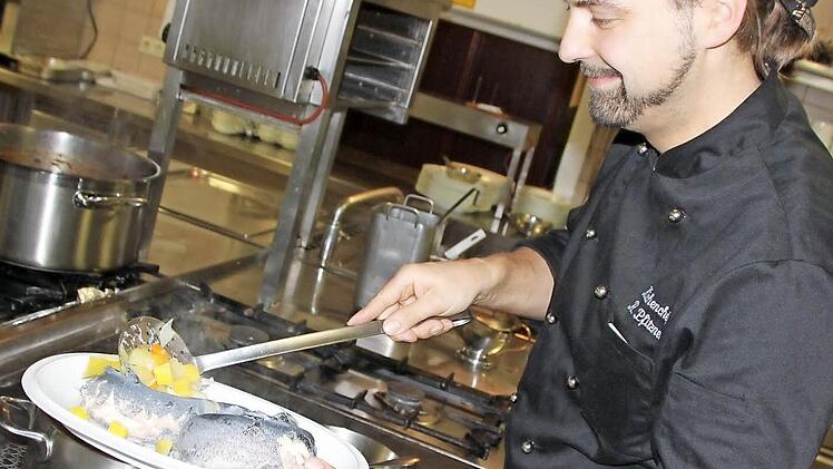 Rico Pfitzner nimmt die fertigen Forellen vorsichtig aus dem Kochtopf und legt sie auf einen Teller. Fotos: Matthias Einwag