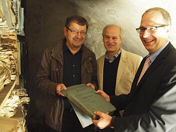 Amtsleiter Hans Vetter, Klaus Rupprecht vom Staatsarchiv Bamberg und Landrat Christian Meißner (von links) blättern bei der bei der offiziellen Übergabe in den alten Akten des Bezirksamts Staffelstein. Foto: M. Einwag