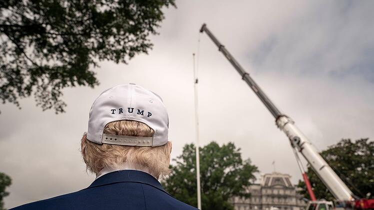 Donald J. Trump blickt auf Arbeiter, die am 18. Juni 2025 auf dem South Lawn des Wei&szlig;en Hauses in Washington, DC, einen riesigen neuen Fahnenmast aufstellen.