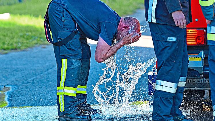 Ein Feuerwehrmann k&uuml;hlt sich bei einem Einsatz ab.SMS|Schalk, Manfred, Schrobenhausen