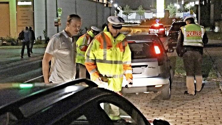 Mit einem Fahrer schaut Tobias Kern dessen Auto an. Im Hintergrund kontrollieren Wolfgang Schmitt und Julia Holzheid einen weiteren Pkw.