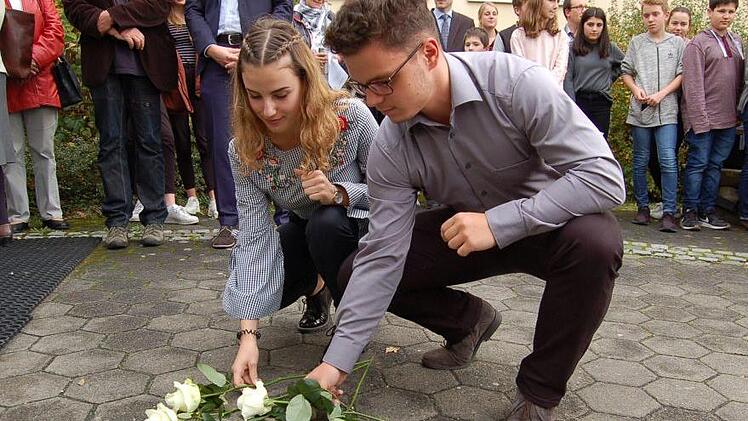 Samira Eberth und Tim Culmbacher legen ihre Rosen am Stolperstein für Edith Frank nieder. Foto: Helke Renner
