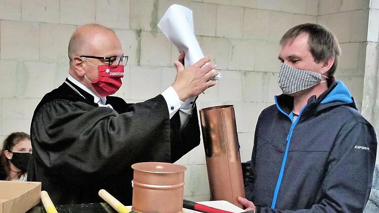 Mathias Hartmann gibt die Urkunde nebst aktuellen Tageszeitungen und mehreren Euro-Münzen in die vorgefertigte Kupferrolle; rechts Herbert Fecker von der Bewohnervertretung, der den Wortlaut der Urkunde verlas. Foto: Werner Reißaus