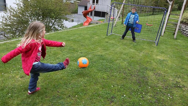 Der Rasen ist sicherlich die wichtigste Pflanze im Familiengarten. Hier testet die kleine Elena die Torwartkünste ihres achtjährigen Bruders Christopher. Foto: Barbara Herbst